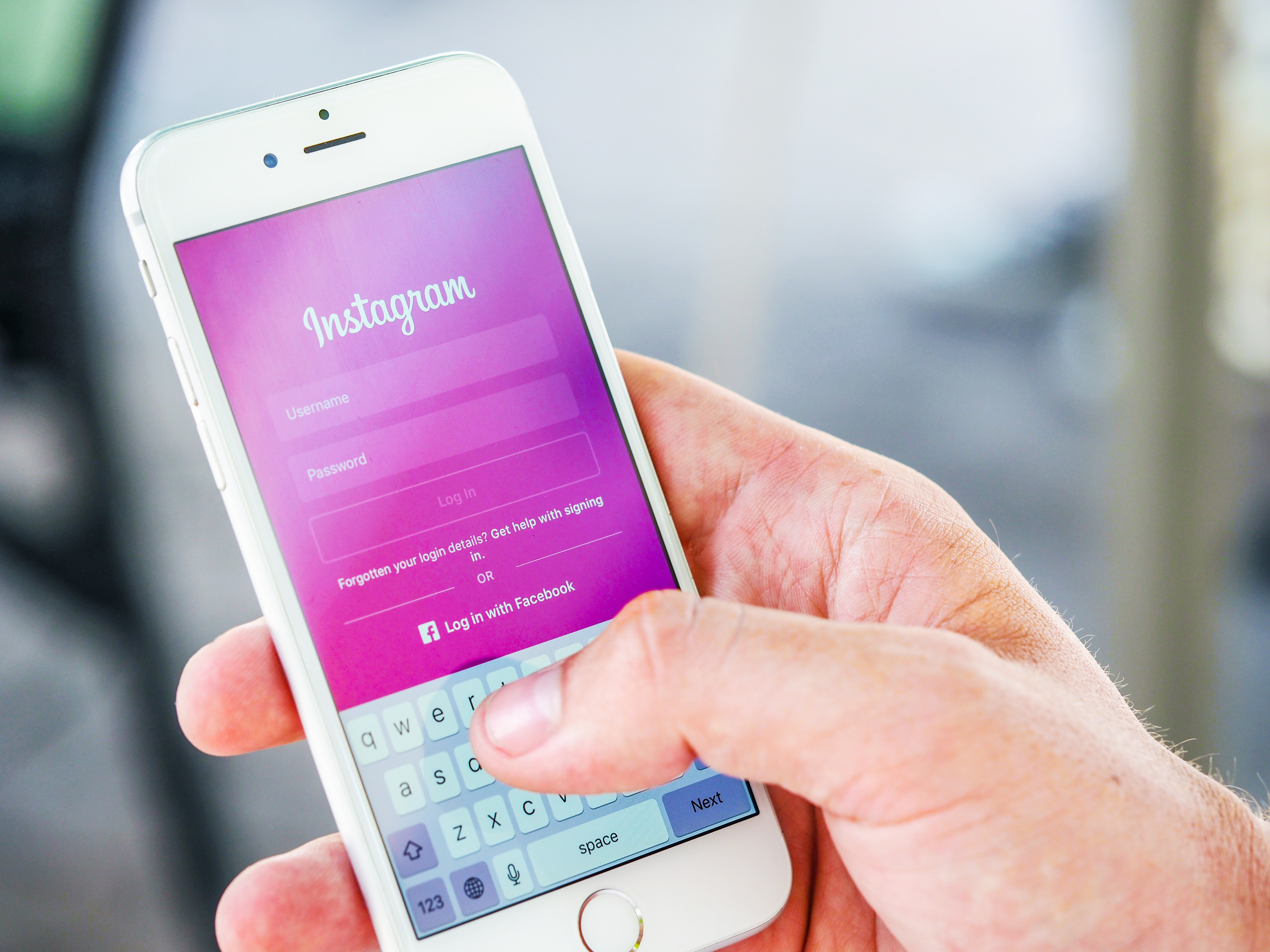 como conseguir seguidores no Instagram - Smartphone em uma mão com a tela de login do Instagram aberta
